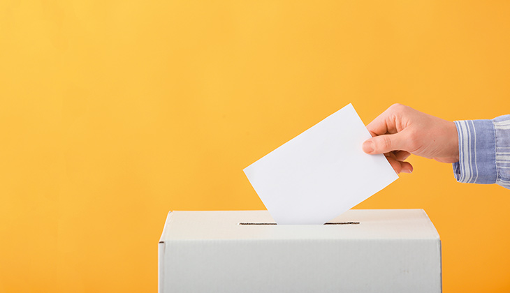 Illustrationsbild på en person som sätter en röstsedel i en valurna.