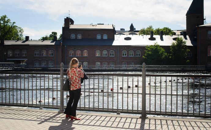 En person tar en bild på Tammerfors ån från en bro.