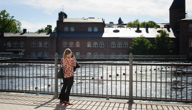 En person tar en bild på Tammerfors ån från en bro.