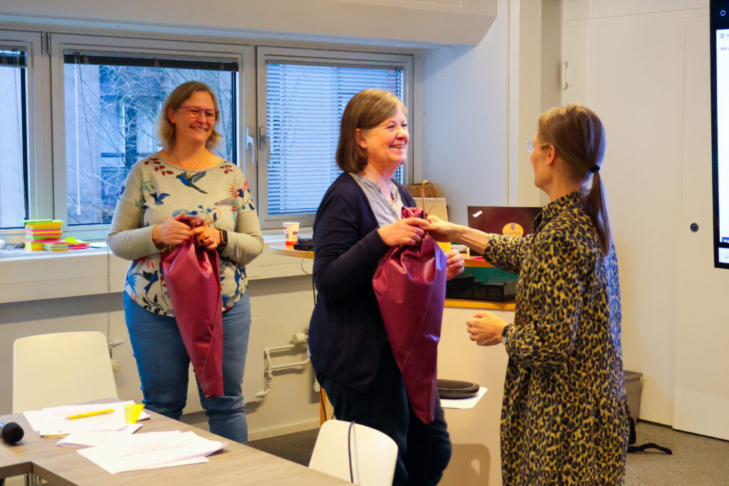 SAMS verksamhetsledare Nina af Hällström överräcker blommor till avgående ordförande Beatrice Wahlström och nyvalda ordförande Pamela Kinnunen.