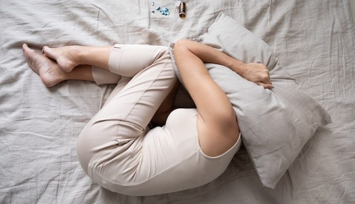 Kvinna som ligger i fosterställning.